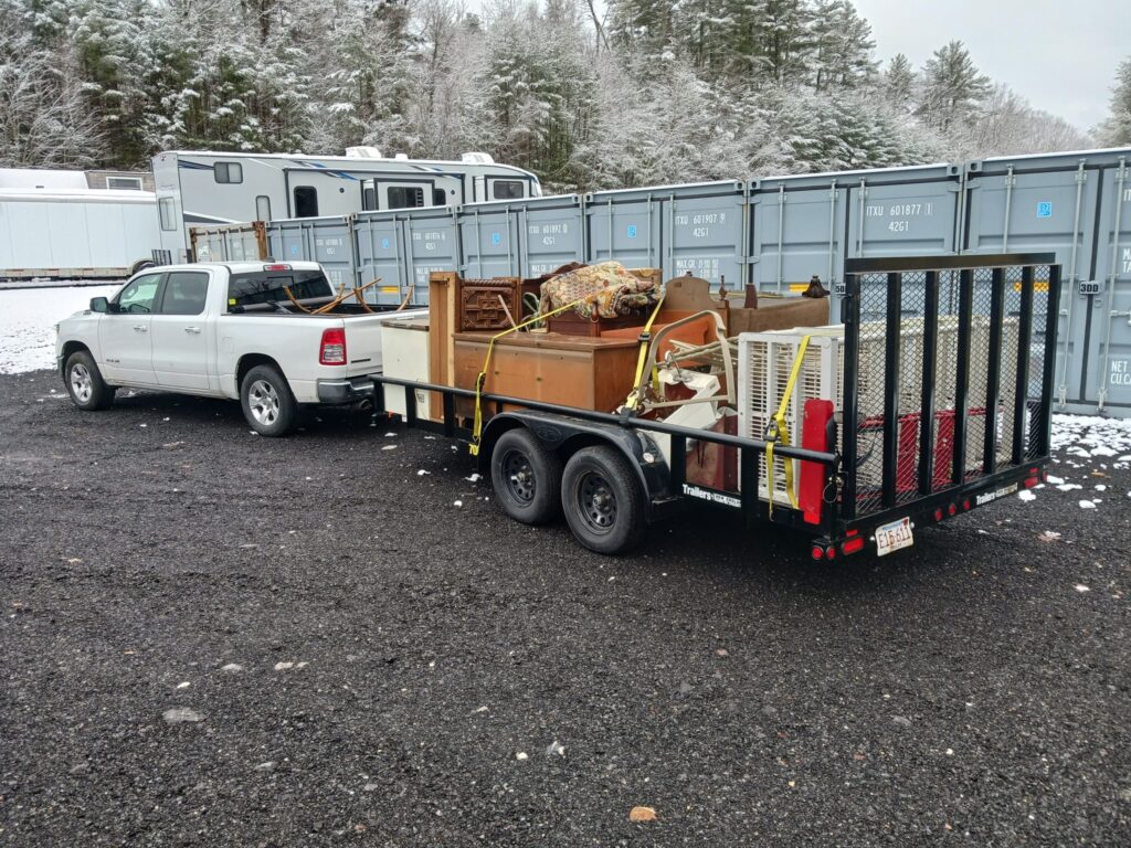 White pick up truck towing household goods on a medium-sized trailer